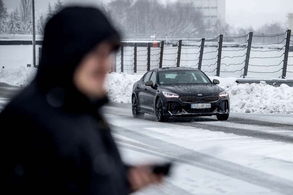 10 Tipps für sicheres Fahren Auto fährt im Schnee, Fahrtrainer im Vordergrund