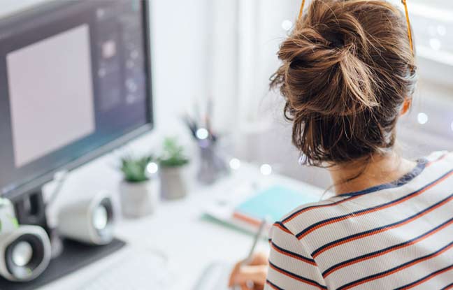Frau arbeitet im Homeoffice und schaut aus dem Fenster