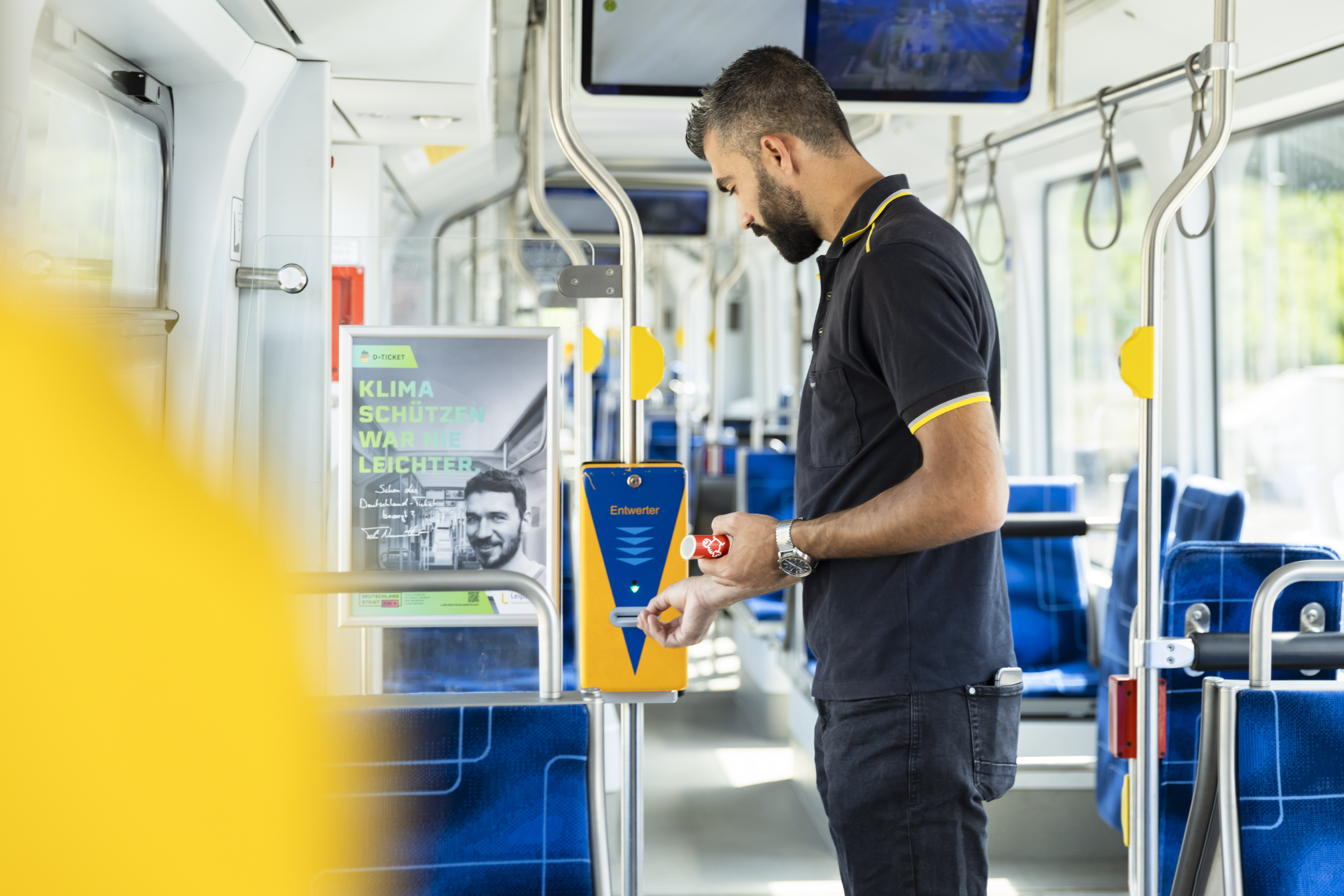 Nazar Arab steht in einer leeren Straßenbahn und entwertet ein Ticket. Man sieht ihn von der Seite.