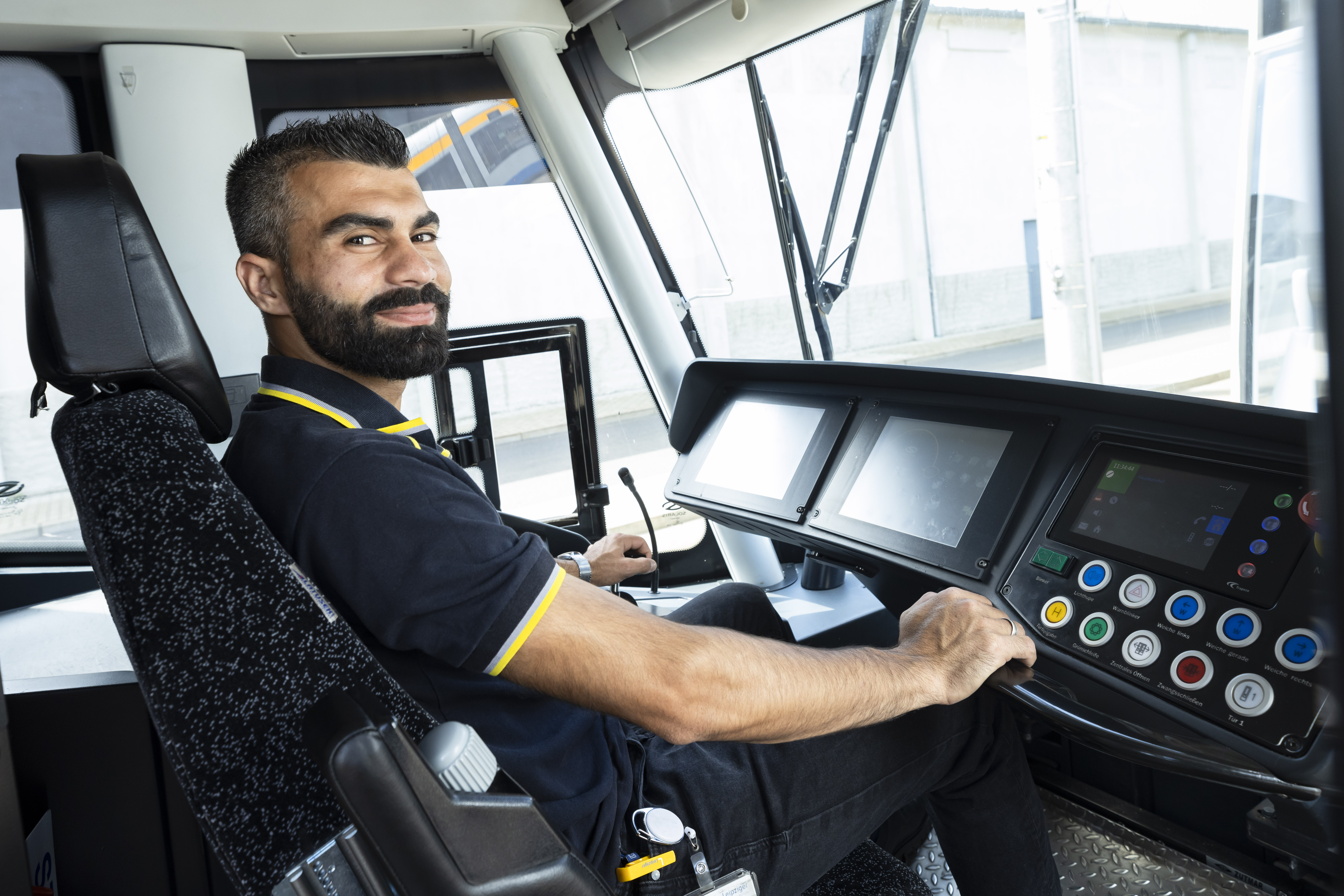 Nazar Arab sitzt am Steuer einer Straßenbahn und lächelt in die Kamera